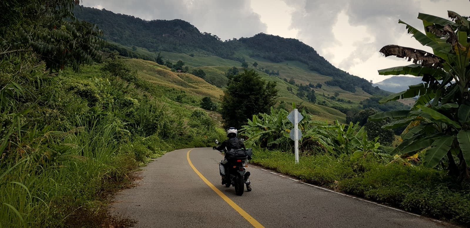A rider on a mountain road through terraced hills in Northern Thailand
