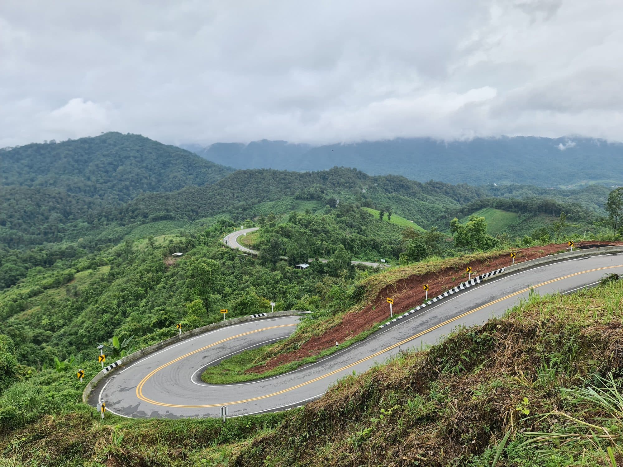 A hairpin stacked above a green valley on a mountain road in Nan province