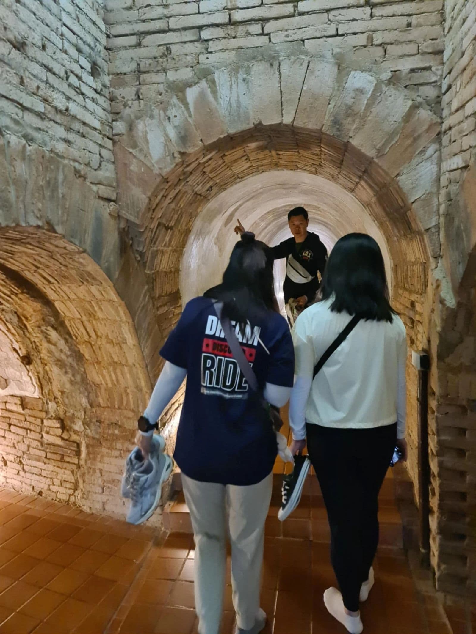 NBT guide explaining a route to two riders inside Wat Umong tunnel, Chiang Mai